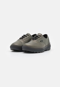 Sapatos sintéticos verde-escuro com um acabamento suave, ponta redonda, atacadores pretos e uma sola de borracha texturizada com pequenas saliências.