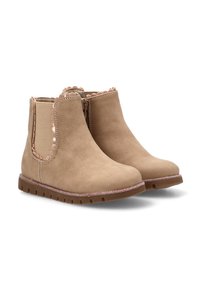 Botas tobilleras beige con una textura de ante suave, paneles laterales elásticos, bordes ondulados y una suela brillante.