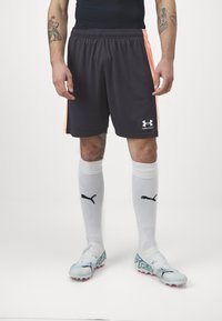 Fekete sportshort, narancssárga oldalsávokkal, könnyű anyagból készült. Fehér zoknival viselve, fekete logóval és világoskék focicipővel.