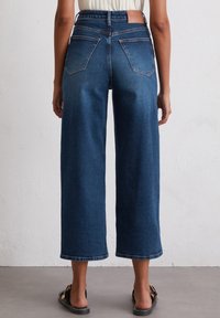 Hoch taillierte Denim-Culottes in Mittelblau, mit lässiger Passform, Gesäßtaschen und sichtbaren Nähten, sowie fransigen Saumdetails.