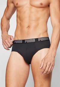 Schwarze Baumwollslips mit einem grauen Puma-Logo-Bund. Das Design bietet eine enge Passform und eine glatte Textur, ideal für Komfort und Unterstützung.