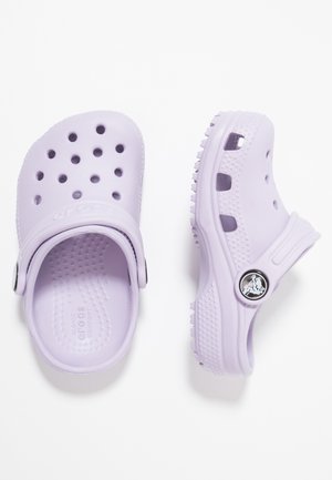Een paar lavendelkleurige Crocs klompen met ventilatiegaten, verstelbare hielbandjes en getextureerde binnenzolen op een witte achtergrond.