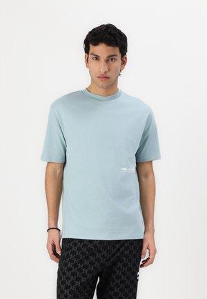 Tricou scurt cu mânecă scurtă, de culoare albastru deschis, fabricat din bumbac moale, având un mic logo alb pe pieptul stâng. Decolteu simplu, tip crew, și croială relaxată.