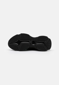 Semelle de chaussure de sport noire avec des motifs de bande de roulement en zigzag texturés, segmentée en cinq zones d'adhérence distinctes.