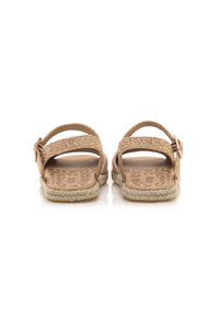 Sandalias trenzadas marrón con dos correas ajustables, plantilla texturizada y un detalle de yute trenzado alrededor de la suela. Diseño plano para facilitar su uso.