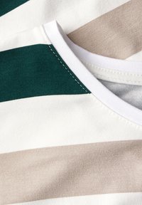T-shirt in cotone con strisce orizzontali in verde scuro, beige e bianco. Collo rotondo con bordo a coste bianche e cuciture visibili.