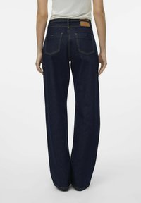 Modre široke hlače iz trpežnega denim materiala. Imajo visok pas, zadnje žepke in svetlosrno usnjeno oznako na pasu.