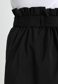 Mustikka hame, jossa on röyhelövyötärö, ja joka on valmistettu sileästä ja kevyestä kankaasta, jossa on kerääntynyt muotoilu.