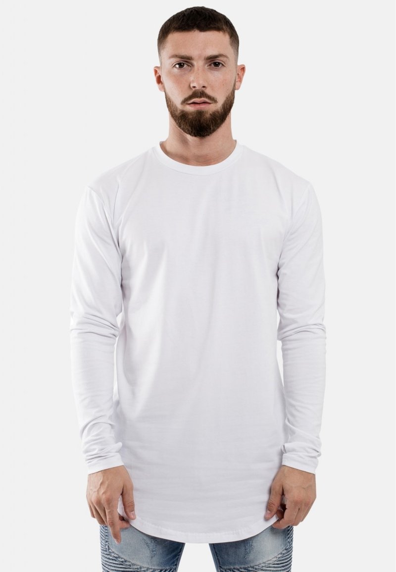 Witte T-shirt met lange mouwen van katoen, met een ronde hals, met een rechte zoom en een ontspannen fit. Draagt met blauwe spijkerbroek.