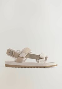 Beige Sandale mit Stoffriemen, verstellbarem Schnallenverschluss, strukturiertem Sohlen und leichtem Design. Verfügt über eine zweifarbige Farbgebung.