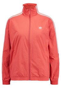 Červená zapínací bunda vyrobená z lehkého materiálu; má stojáček a bílé pruhy na ramenou. Malé logo na hrudi.