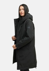 Parka noire avec capuche, dotée d'une fermeture éclair à l'avant, de boutons-pression et de cordons réglables. Fabriquée en tissu texturé résistant à l'eau.