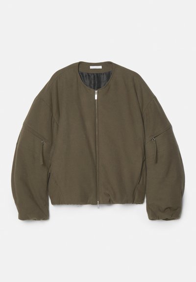 Giacca bomber cropped verde oliva con scollatura rotonda, zip frontale completa e due tasche laterali con zip. Realizzata in un tessuto morbido e testurizzato.