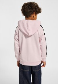 Lichtroze hoodie met zwarte zijstrepen, geribbelde manchetten en zoom. Zachte stof, normale pasvorm, de achterkant toont de vorm van de capuchon.