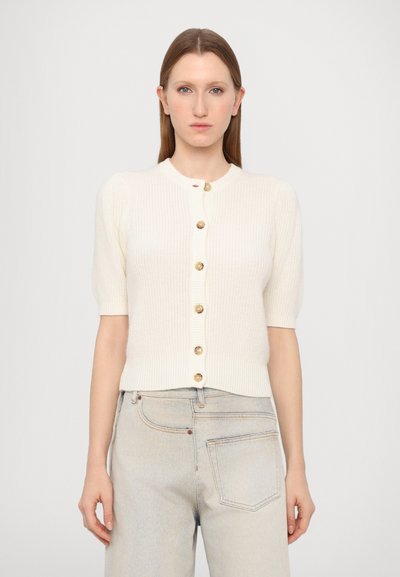Cardigan à manches courtes en crème, en maille côtelée, avec un col rond et six boutons dorés sur le devant. Texture douce et coupe ajustée.