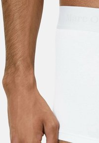 Weiße Baumwoll-Boxershorts mit einem glatten, elastischen Bund, der mit "Marc O." geprägt ist. Der Stoff wirkt weich und hat minimale Nähte.