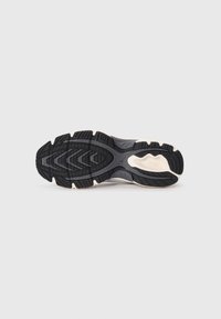 Running shoe outsole featuring a durable black rubber tread with a zigzag pattern, white accents, and a textured surface for traction.