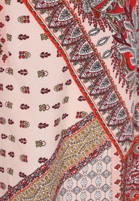 Tessuto multicolore con intricati motivi paisley, floreali e geometrici. Texture morbida con una base rosa chiaro e vivaci accenti rossi, gialli e neri.