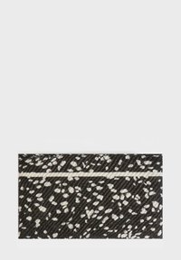 Tessuto nero con un motivo maculato bianco, caratterizzato da una striscia orizzontale bianca. Superficie texture con un design moderno.