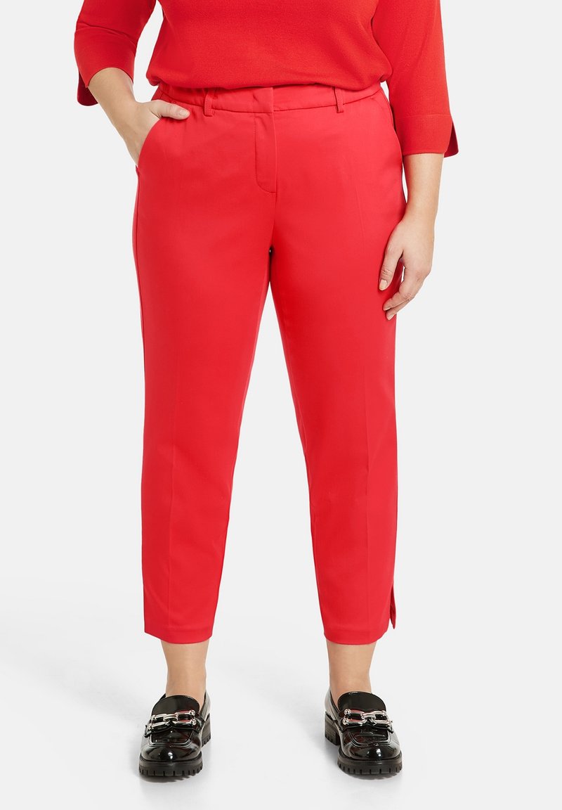 Pantalon rouge fuselé à la texture lisse, doté d'une poche avant et de fentes latérales, associé à des mocassins vernis noirs.