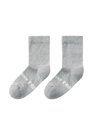 Coppia di calzini grigi alla caviglia con polsini a coste e testo parziale bianco sulle suole, posati distesi su uno sfondo bianco.