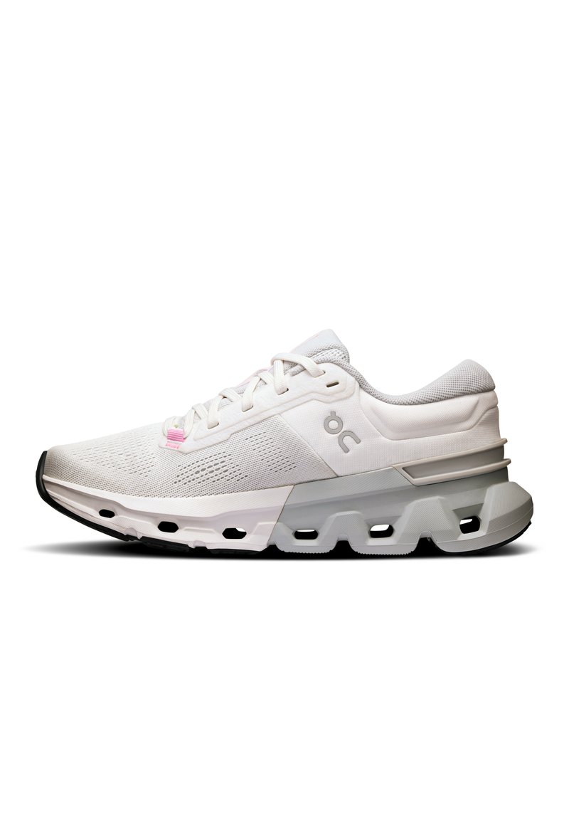 Chaussure de sport blanche avec une tige en maille texturée, accentuée de détails gris clair et rose. Présente une semelle épaisse avec des sections découpées.