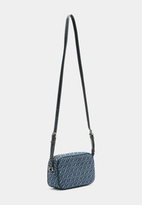 Niebieska torba na ramię z wzorem, o prostokątnym kształcie, z regulowanym paskiem, złotymi elementami i teksturowanym materiałem z geometrycznym wzorem.