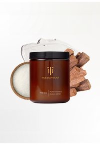 Bocal en verre ambre avec couvercle noir, étiqueté "Gommage au Sucre Pure Radiance." Accompagné de sucre, de gel lisse et de morceaux de bois.