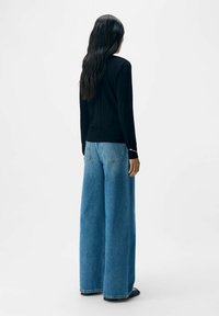 Sort langærmet top parret med oversized blå denim jeans. Jeansene har en løs pasform og en let falmet tekstur.