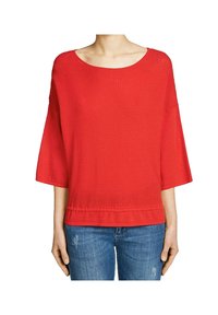 Rotes Strickoberteil mit weiter Bootsausschnitt, Dreiviertelärmeln und einem strukturierten Muster. Kombiniert mit blauen Jeans.