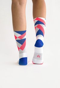 Multi-colored knee-high socks featuring geometric patterns in pink, blue, and white, with a textured finish and reinforced toe sections.