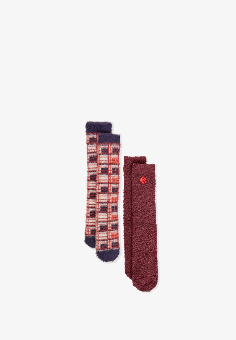 Un par de calcetines con un diseño de cuadro rojo y azul marino, y otro par liso burdeos con textura peluda y un pequeño acento rojo.