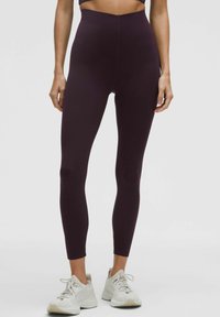 Aukštu liemeniu purpurinės tamprės iš lygaus tamprios medžiagos, siaurėjančios formos, su siūlės detale. Derinamos su šviesiai pilkais sportbačiais.