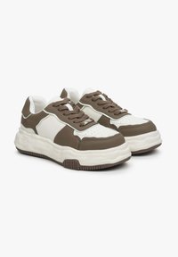 Brązowe i białe sneakersy z grubą podeszwą, wykonane z materiałów skórzanych i siateczkowych, z perforowanym noskiem oraz kontrastującymi akcentami na cholewce.