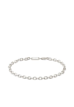 Hopeinen ketjurannekoru, jossa on soikeat lenkit ja jättiläisrapulukko, johon on kaiverrettu "SEIZMONT", valkoisella taustalla.