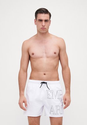 Shorts da bagno bianchi con cordoncino nero, con la scritta "EMPR" e "ARM" stampata in lettere grasse. Il materiale sembra leggero e a rapida asciugatura.