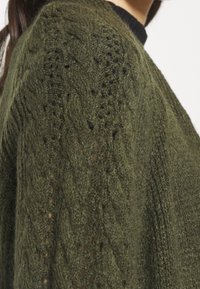 Olivgrön stickad cardigan med kabelmönster och texturerad yta, med rundad halsringning och långa ärmar.