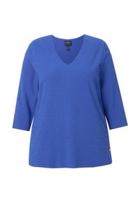 Top azul de cuello en V con mangas de tres cuartos, patrón texturizado y un pequeño logo acentuado cerca del dobladillo. Hecho de una tela suave y elástica.