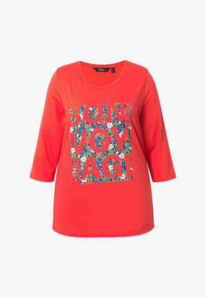 Maglia rossa a maniche lunghe con scollo rotondo e grafica a blocchi floreali con la scritta "BON VOYAGE" in caratteri grassetto.