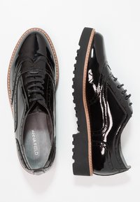 Oxfords en cuir verni noir avec un design à boutilever, présentant un système de laçage, une surface texturée et une semelle épaisse et robuste avec des accents marron.