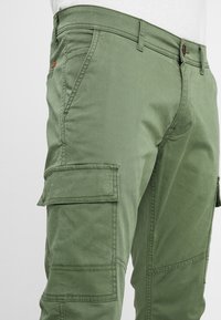 Groene katoenen cargobroek met zijzakken, een knoopsluiting en gestikte details. Soepele textuur, comfortabele pasvorm en casual ontwerp.
