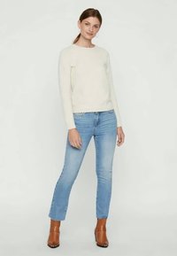 Cream sweater, light blue jeans, brown ankle boots. Sweater has long sleeves, round neckline; jeans are fitted, slightly flared at the hem.