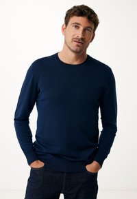 Marineblauer Langarmpullover aus strukturiertem Strickstoff. Mit Rundhals, Rippbündchen und -saum, kombiniert mit dunklen Denim-Jeans.
