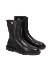 Czarne skórzane botki za kostkę o gładkim wykończeniu, z okrągłym noskiem i płaską gumową podeszwą. Zawierają złoty akcent logo po boku.