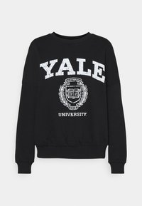 Felpa nera con testo bianco: "YALE" e "UNIVERSITY", con un emblema centrale. Maniche e orlo a coste, vestibilità comoda. Materiale in cotone morbido.
