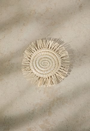 Round woven mat made of natural fibers. Features a spiral pattern with fringe edges. Color is light beige with a textured surface.
