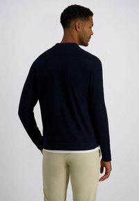 Marineblauer Pullover mit Polokragen, langen Ärmeln und einem schlanken Design. Hergestellt aus weichem Stoff, mit geteiltem Saum und gerippten Bündchen.