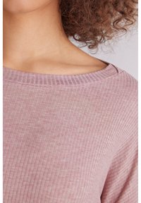 Rosa ribbad tröja med vid halsringning, med en mjuk textur och framträdande vertikala linjer. Skräddarsydd för en avslappnad passform.