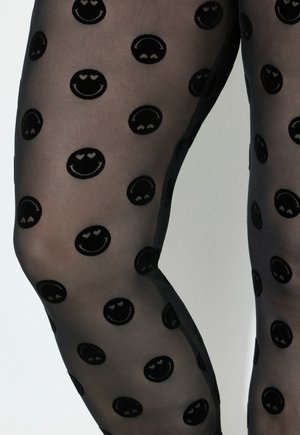 Zwarte doorschijnende panty’s met verhoogde zwarte glimlachende gezichten, die hartvormige ogen hebben, gelijkmatig verdeeld over de stof.