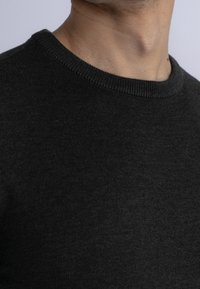 Dark gray knitted sweater featuring a round neckline and ribbed edges. The texture is smooth and even, with subtle stitch details.